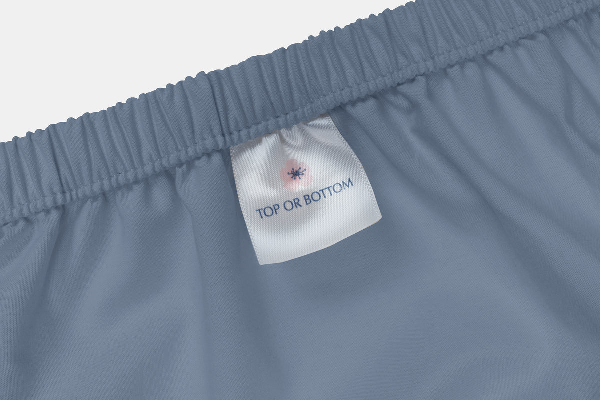 Light blue fitted bed sheet with label indicating top or bottom side, made in USA