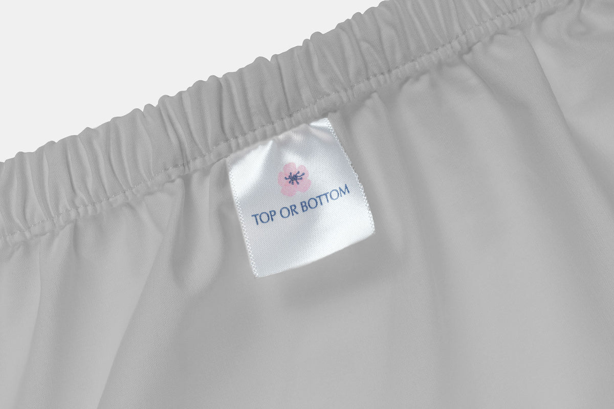 White fitted bed sheet label with pink flower and blue text